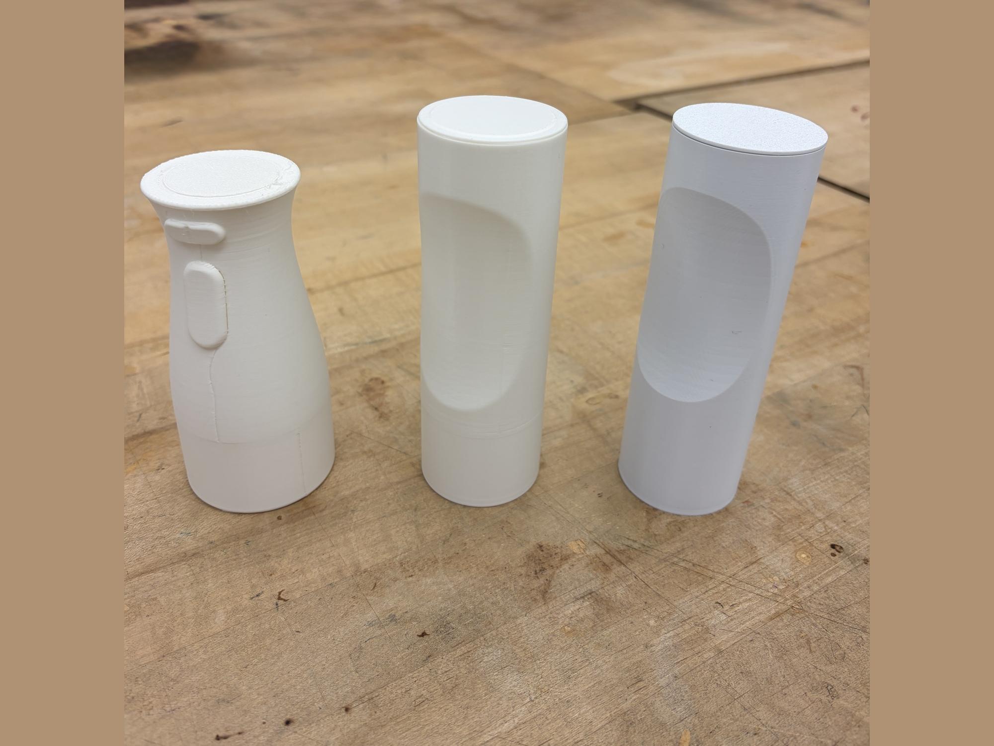Three 3D-printed prototype iterations side by side on a workbench